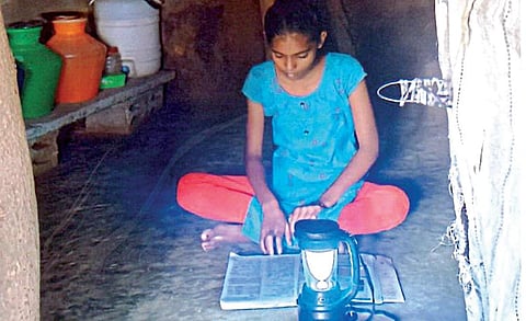 சோலார் விளக்கில் படிக்கும் மாணவி.