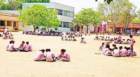 ஓசூர் அருகே மத்திகிரி அரசு மேல்நிலைப் பள்ளி மைதானத்தில் உச்சி வெயிலில் மண் தரையில் அமர்ந்து சாப்பிடும் மாணவர்கள்.