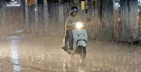 கோவை சிங்காநல்லூர் காமராஜர் சாலையில் மழையில் நனைந்த படி செல்லும் வாகன ஓட்டி. படம்: ஜெ.மனோகரன்