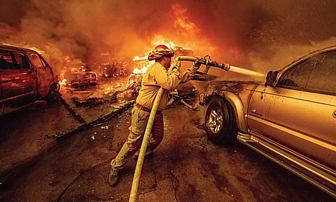 அமெரிக்காவின் லாஸ் ஏஞ்சல்ஸ் நகரில் பற்றி எரியும் காட்டுத்தீயை அணைக்க உயிரை பணையம் வைத்து தீரத்துடன் போராடும் தீயணைப்பு படை வீரர்.படம்: பிடிஐ