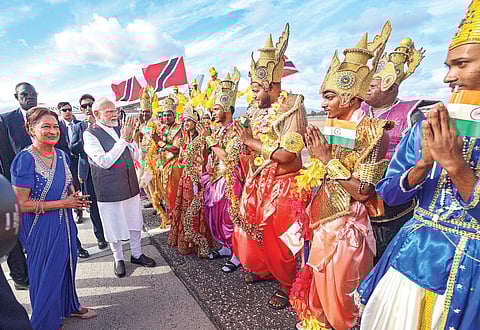 டிரினிடாட் அண்ட் டொபாகோ நாட்டின் தலைநகர் போர்ட் ஆஃப் ஸ்பெயினில் உள்ள சர்வதேச விமான நிலையத்தில், இந்துமத கடவுள்கள் போல வேடம் அணிந்த கலைஞர்கள், பிரதமர் மோடிக்கு சிறப்பான வரவேற்பு அளித்தனர். உடன், டிரினிடாட் பிரதமர் கம்லா பெர்ஷத். படம்: பிடிஐ