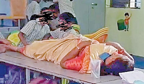 வகுப்பறையில் தலைமை ஆசிரியரின் காலை அழுத்திவிடும் மாணவர்கள்.