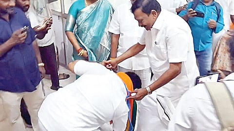 கும்மிடிப்பூண்டி திமுக வேட்பாளர் டி.ஜெ.கோவிந்தராஜனின் காலில் விழுந்து ஆசீர்வாதம் வாங்கிய அதிமுக வேட்பாளர் சுதாகர்.