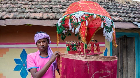 a Santhali man holding a chadar badar set