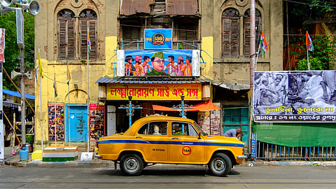 A yellow ambassador taxi parked in front of the 106-year-old Laksminarayan Shaw & Sons snacks shop.