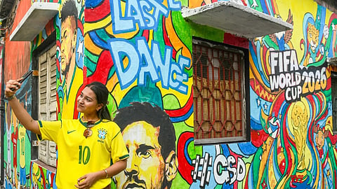 A woman poses in front of a football mural in Kolkata.