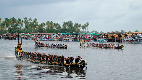 A snake boat with rowers in sync and a front leader giving cues, amidst the race-day crowd.