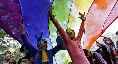 Participants dance under a a rainbow flag as they attend the sixth Delhi Queer Pride parade