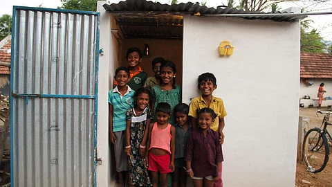 Children pose outside a toilet in India
