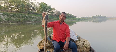 Arun Sahni displays his first catch of the day on the banks of the Bagmati River in Hayaghat, Darbhanga, Bihar. The early morning light reflects off the water as he begins another day of traditional fishing.