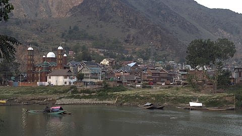 Boats line the banks of the Jhelum River as workers prepare to collect sand, a common practice in Kashmir despite restrictions on riverbed mining.