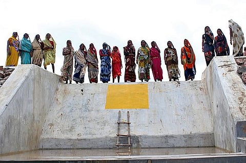 The women stand on the check dam they built while restoring the Baba Talaab. (Image: Parmarth Samaj Sevi Sansthan)