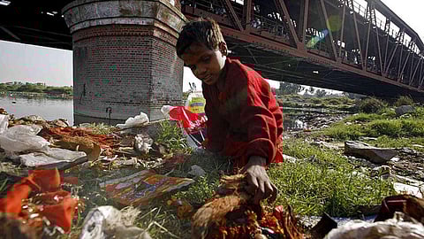 A child collects garbage at Yamuna ghat in Delhi