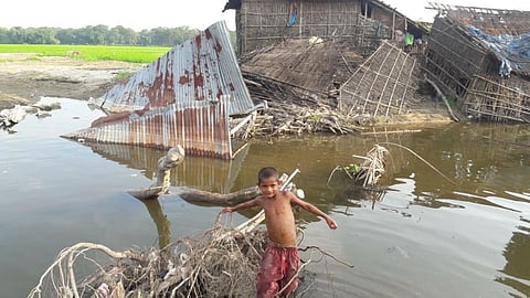 A boy stands in front of houses destroyed by flood in Karimganj district, Assam.