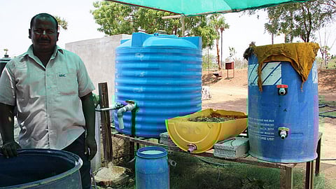 Alagesan with the barrel used to ferment cow dung