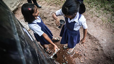 Children drinking rainwater collected in tanks at Melamati Government Junior Basic School, Jorhat (Assam).