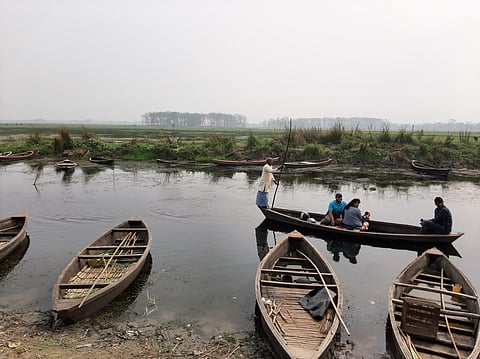 झील के बचे हुए पानी में पर्यटकों को घुमाते कबरताल के मछुआरे।