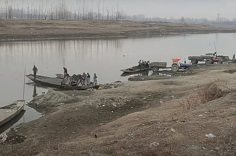 श्रीनगर के लासजान में, झेलम नदी के तट पर नावों से ट्रैक्टरों तक रेत ले जाते मज़दूर।