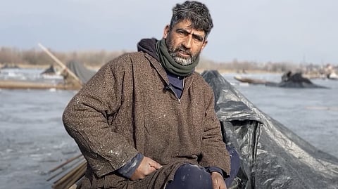 फारूक अहमद डार आंचर झील में अपनी नाव में बैठे हैं, जहां कभी वे अपने परिवार के लिए मछली पकड़ते थे। झील के प्रदूषण ने अब उनकी रोज़ी-रोटी छीन ली है।