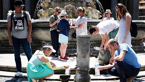 फ्रांस में गर्मी में तपती धूम में प्यास बुझाने के लिए पानी भरते लोग।
