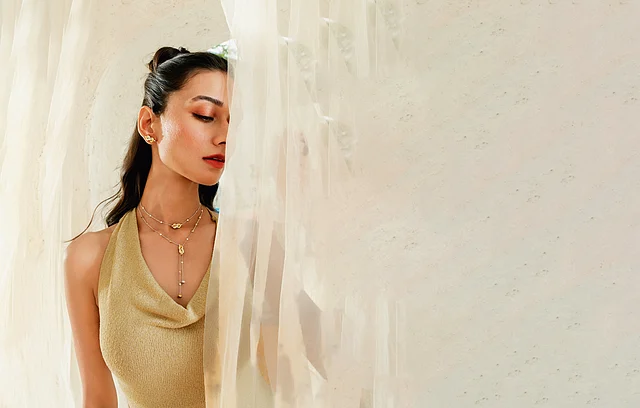 Model wearing layered dual-tone gold necklaces with delicate gemstones from Hazoorilal Legacy’s Summer of Zoori collection.