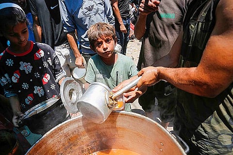 Palestinians displaced by conflict line up for food from a charity in Deir el-Balah, Gaza Strip, on June 26, 2024.