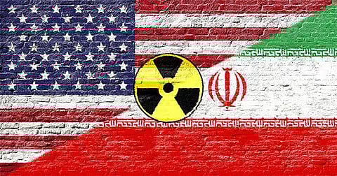 U.S. and Iran - Flags on a brick wall with a nuclear symbol.