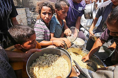 Displaced Palestinians in Deir el-Balah line up to receive food provided by charitable organizations.