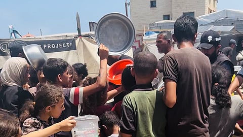 Palestinian children line up to collect food aid.