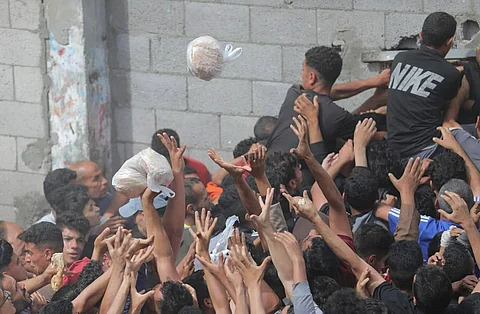 Starving Gazans reach desperately for a piece of bread.