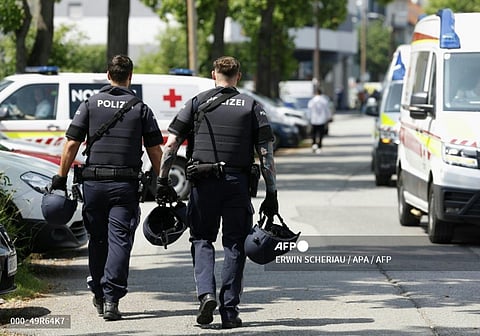 Two policemen walk past ambulance cars in a street close to a school whereseveral people died in a shooting, on June 10, 2025 in Graz,