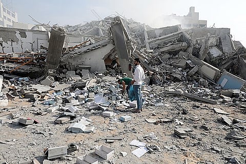 Palestinians inspect the ruins of Watan Tower destroyed in Israeli airstrikes in Gaza city, on October 8, 2023.