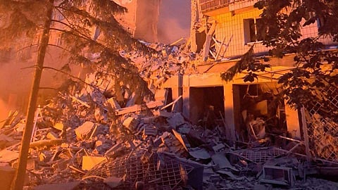 A devastating scene unfolds as a building in Kyiv lies in ruins, its structure split and crumbling amidst a cloud of dust and smoke.
