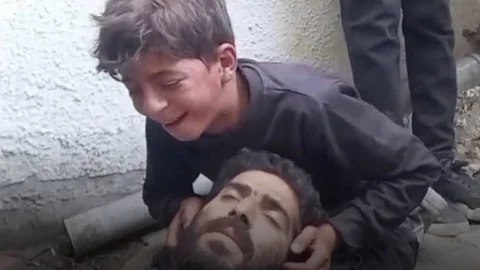 A child mourning over his deceased father in Gaza, a poignant illustration Israel's genocidal actions.