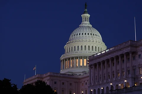 U.S. Capitol at dusk with illuminated dome and clear silhouette against a deep blue sky.