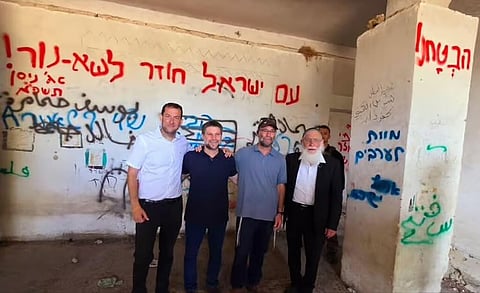 Bezalel Smotrich (second from the left) proudly posing in the occupied West Bank next to a large graffiti which says “Death to the Arabs”.