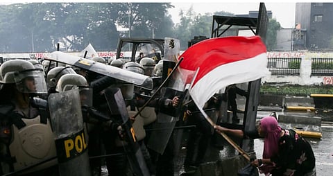 A woman confronting riot police with an Indonesian flag during protests, in Jakarta, Indonesia.