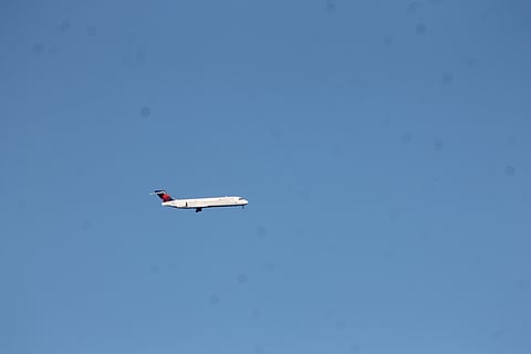 A Boeing 717-200 flying over the Pacific Ocean towards John Wayne International Airport.