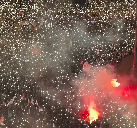 Belgrade students protesting with thousands holding up phone lights in a striking display.