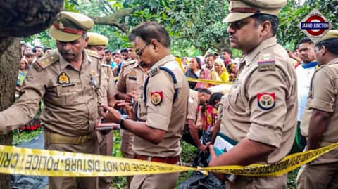 Police personnel investigate after the bodies of two girls were found hanging from a tree, at Kayamganj area in Farrukhabad, Tuesday, Aug. 27, 2024