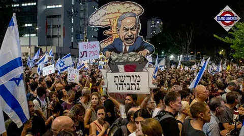 A protester in Tel Aviv, Israel, on Sept. 1 carries a poster reading in Hebrew "Netanyahu's Legacy" at a mass demonstration condemning Prime Minister Benjamin Netanyahu and his handling of the hostages being held by Hamas in Gaza.