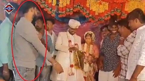 Man collapses on stage after greeting couple, presenting gift to friend.