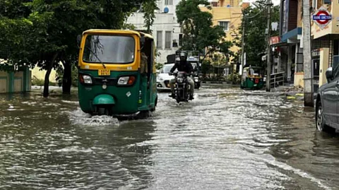 Vehicles drive through flooed roads at HRBR Layout in Bengaluru following heavy overnight rains in Bengaluru on May 19, 2025.
