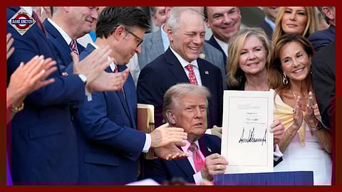 US President Donald Trump holds up his signed signature bill of tax breaks and spending cuts.