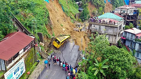 People stand near a road that washed away due to a landslide, on Saturday. Reportedly, Four people killed in the state due to landslide.