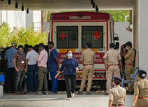 Medics and police personnel outside the mortuary of a hospital, where victims of the Air India plane crash were admitted, in Ahmedabad, Sunday
