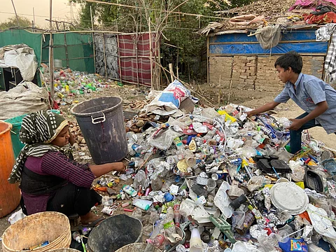 A Rohingya refugee woman and a child picking rags in a heap of waste in Jammu city.