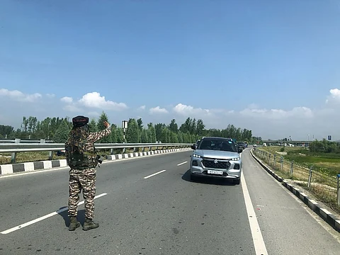A CRPF man signals the vehicles moving towards south Kashmir along the new NH44 near Lasjan, on the outskirts of Srinagar city, to stop, as the convoy of pilgrims need to pass, on Friday July 11, 2025.