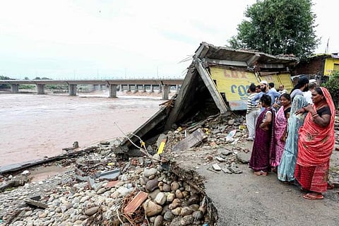 Residents gather near a damaged road along the banks of overflowing Tawi river after heavy rains induced flood in Jammu on August 27, 2025.