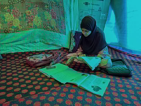 Shabnam Sidiq studies her books inside the tarpaulin tent where she prepared for her Class 12 examinations in Kathward, Pulwama, Kashmir.